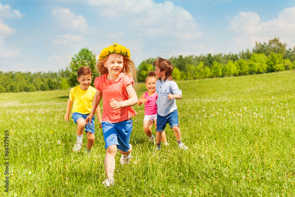 Happy running kids in green field during summer