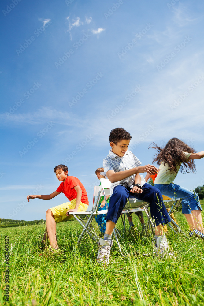 孩子们玩游戏，在外面的椅子上坐得很快