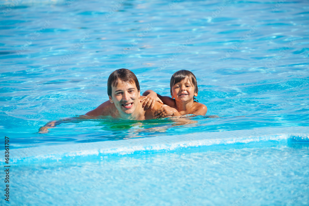 微笑的男人和男孩在游泳池