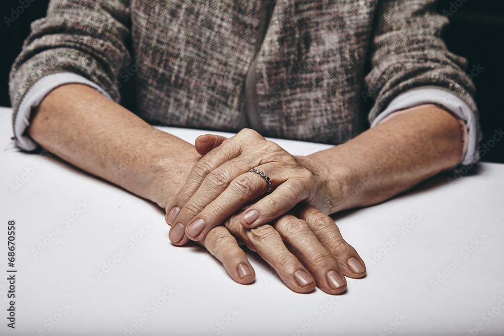老妇人的手放在灰色的表面上
