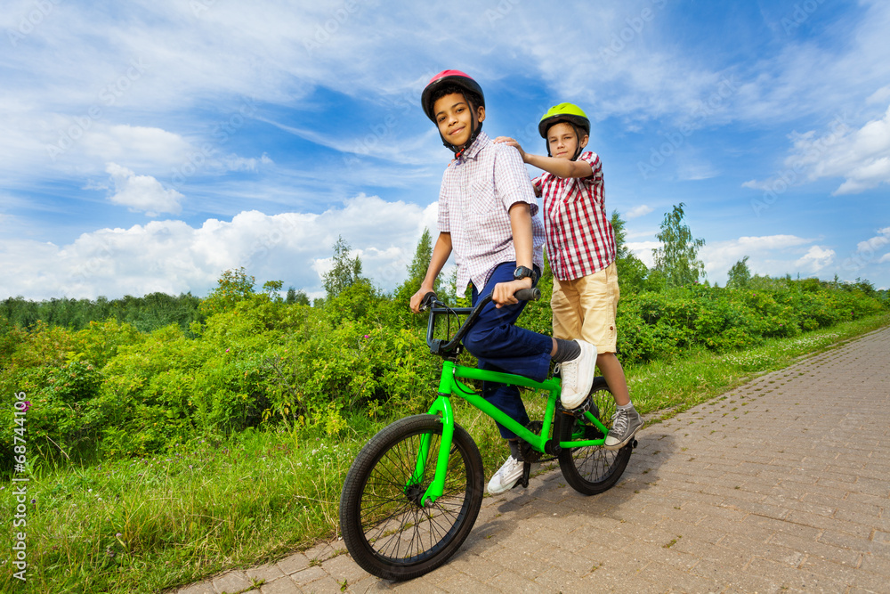 两个男孩骑着同一辆自行车，都站着