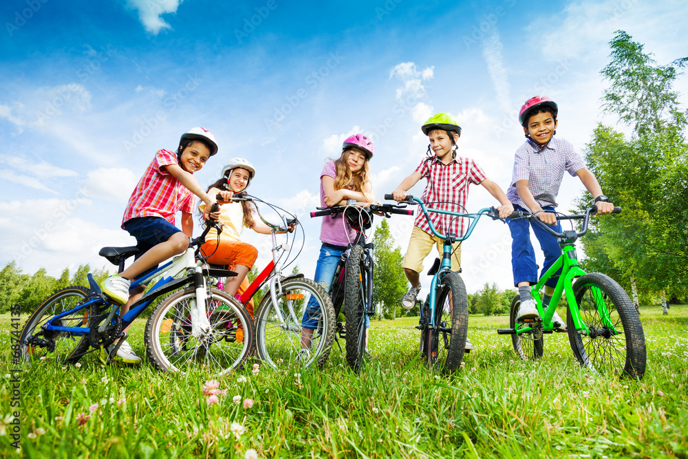 Children in colorful helmets hold their bikes