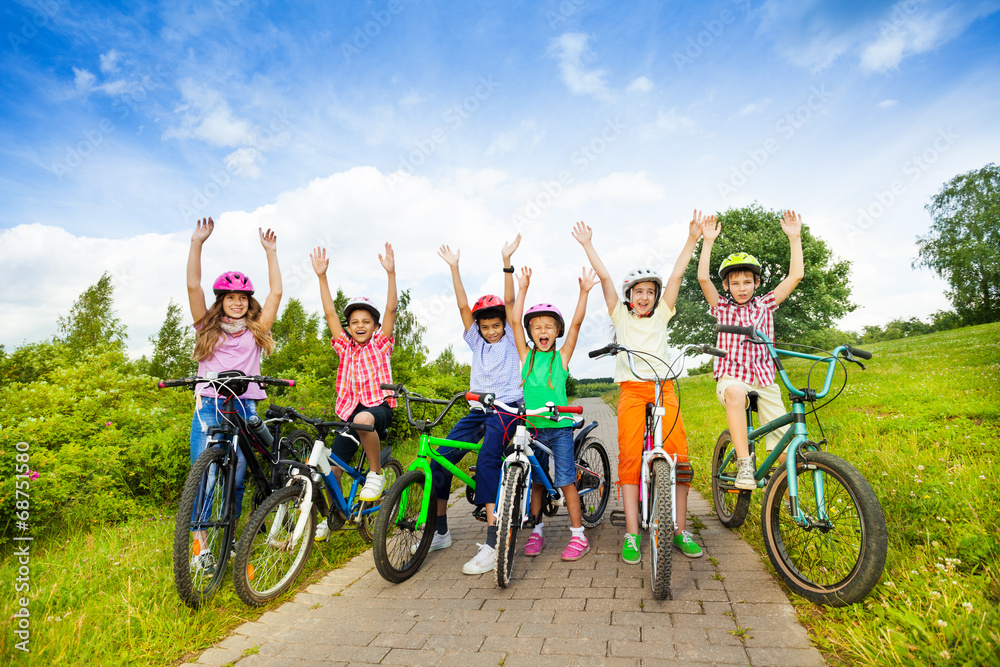 戴着头盔、骑着自行车、双手高举的兴奋的孩子们