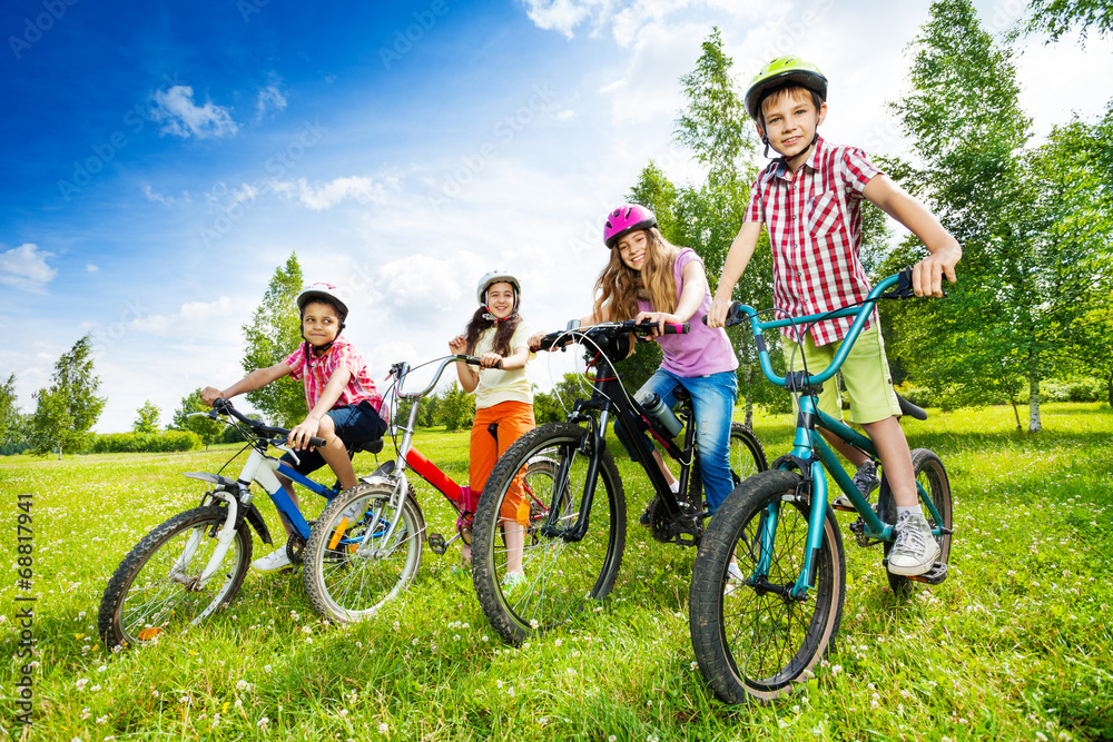 戴着彩色自行车头盔、抱着自行车的快乐孩子