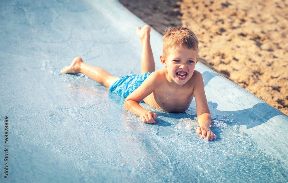 Child on water slide at aquapark, summer holiday