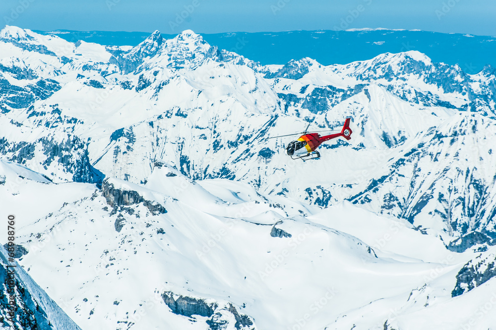 红色直升机在少女峰地区的雪山上空飞行