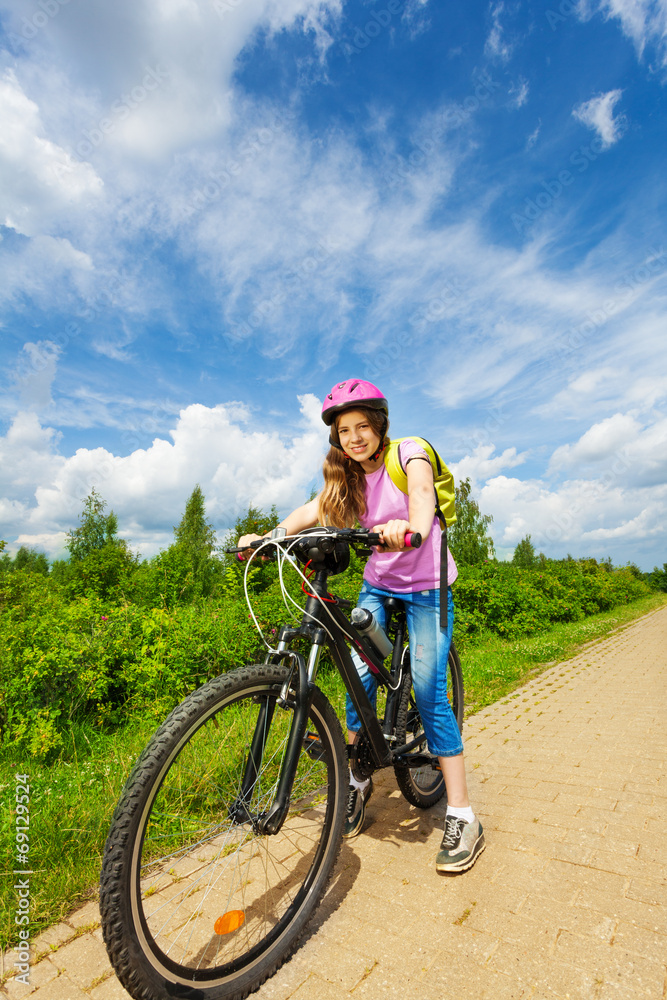戴着粉色头盔的微笑女孩准备骑自行车
