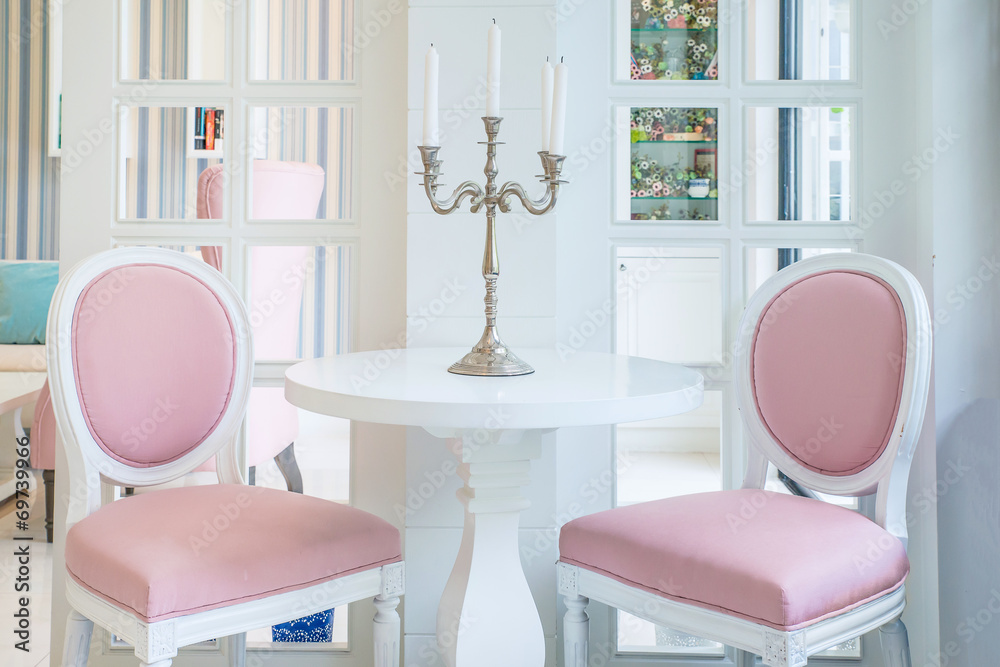 客厅桌子上有蜡烛的白色桌子和粉色椅子