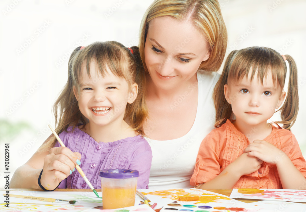 children twin sisters draw paints with her mother