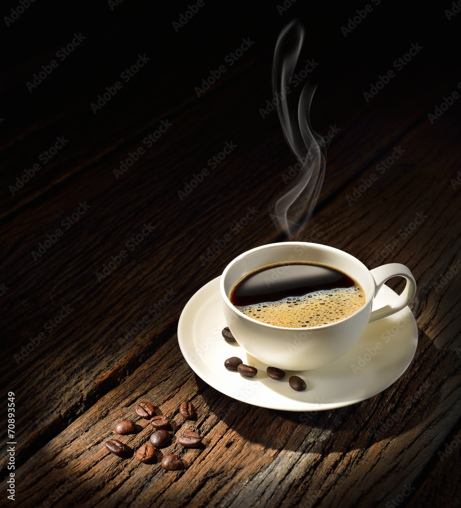 旧木桌上的一杯烟熏咖啡和咖啡豆