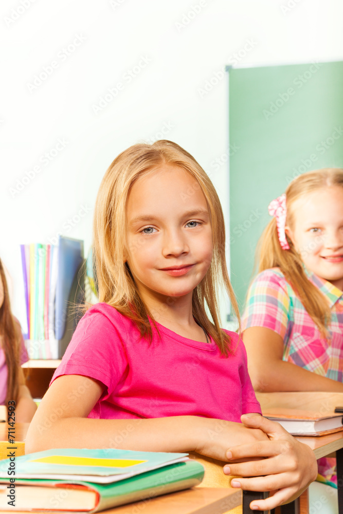 穿着粉色T恤的小女孩坐在桌子旁看着