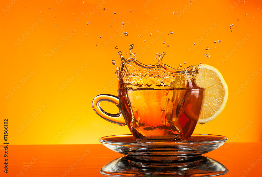 橙色背景的玻璃杯里溅出来的茶