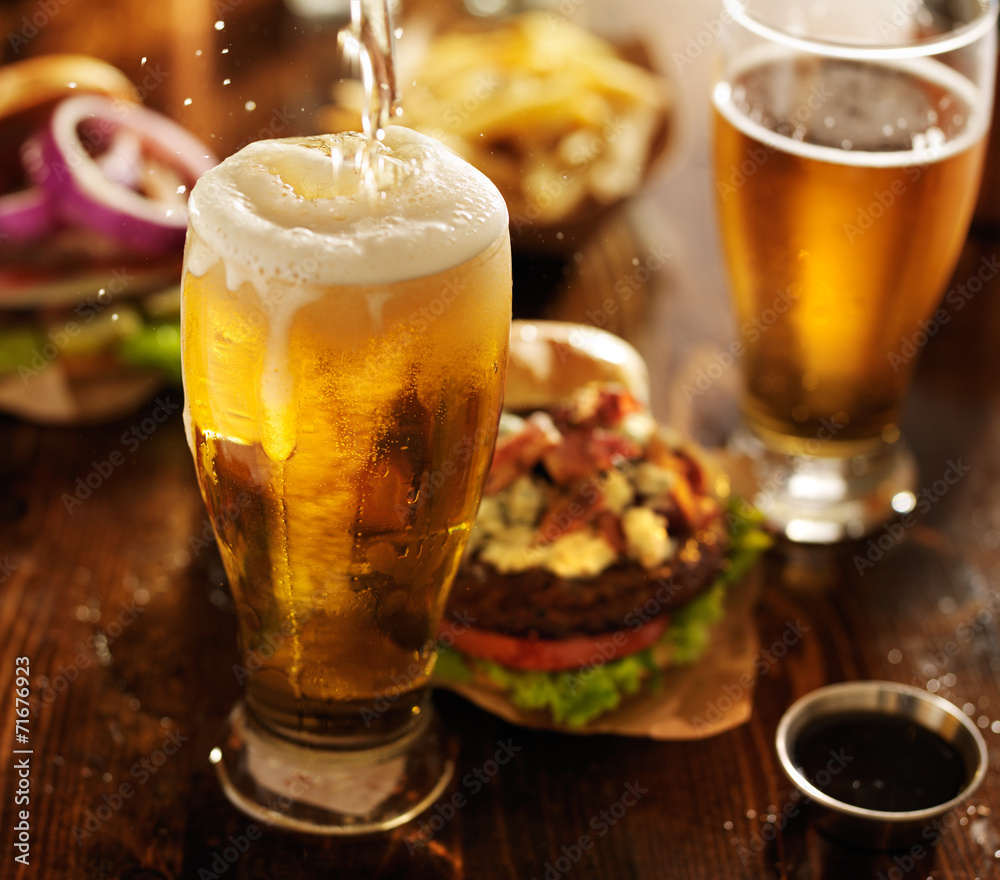 啤酒与美味汉堡一起倒进玻璃杯