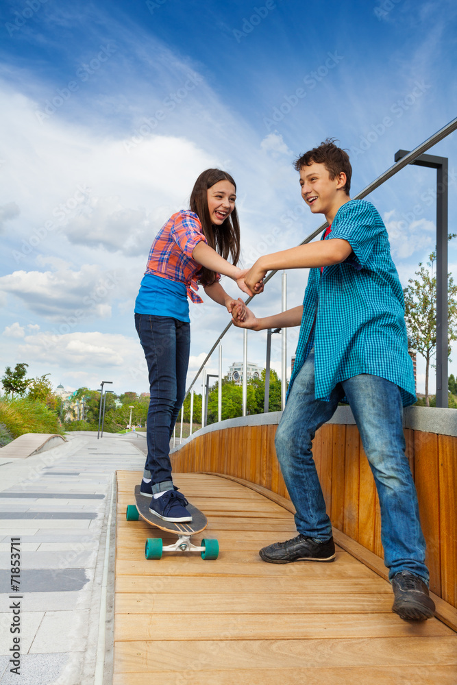 女孩牵着男孩的手学滑板