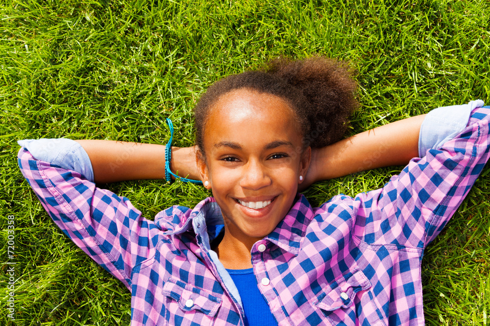 微笑的非洲女孩在夏天躺在草地上