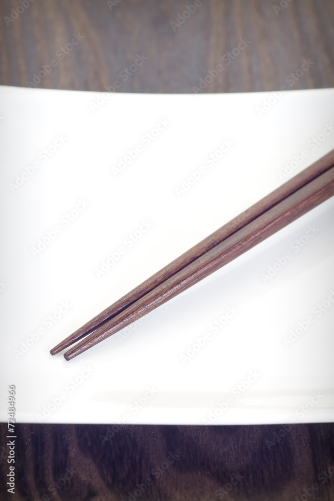 空白盘子上的棕色木筷子