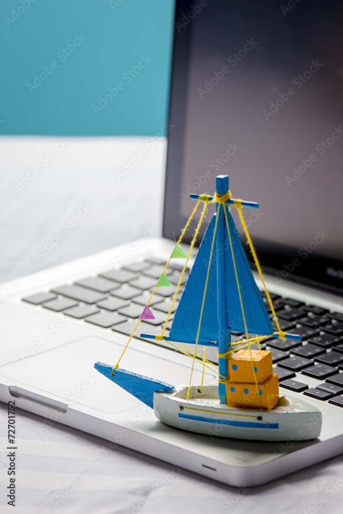 笔记本电脑上的船玩具，旅行概念。