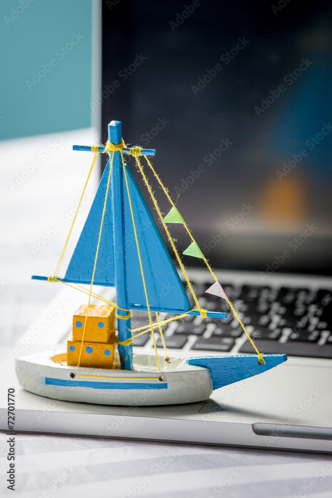 笔记本电脑上的船玩具，旅行概念。