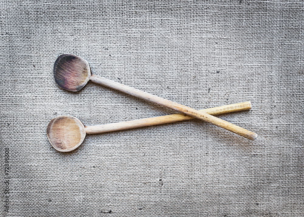 两个质朴的木制烹饪勺，覆盖在麻衣表面