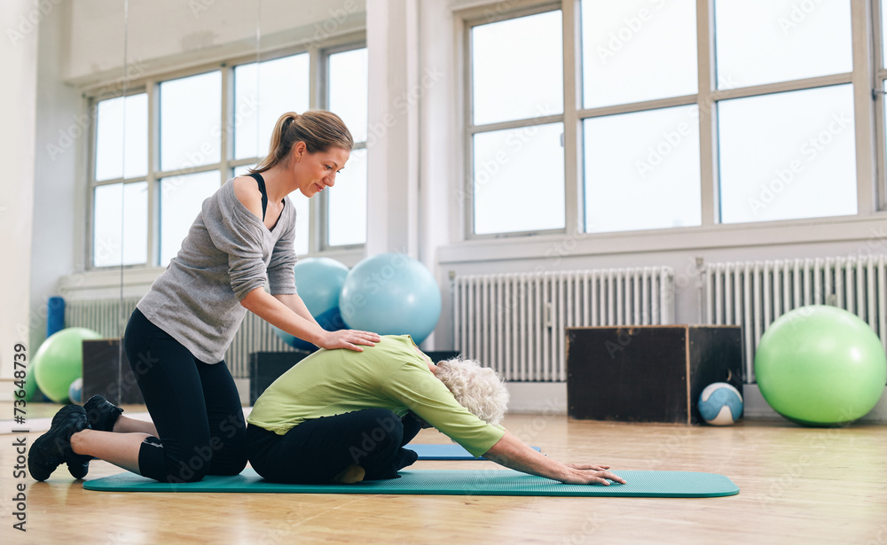体能教练帮助老年妇女做瑜伽