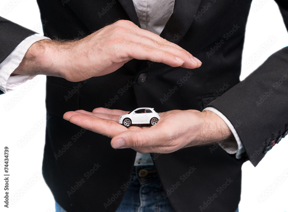 Businessman in black suit holding small car model