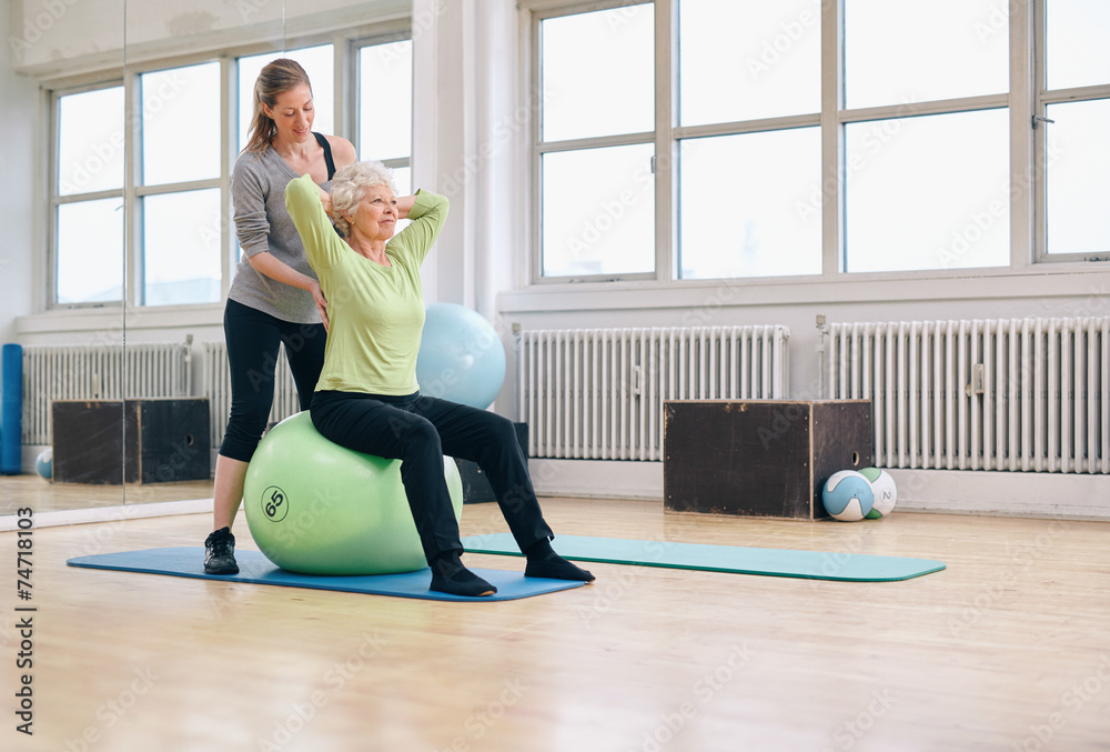 女教练帮助老年女性在健身房锻炼