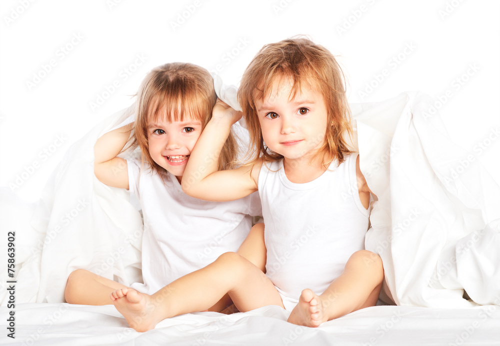 快乐的小女孩双胞胎妹妹在床上玩得很开心