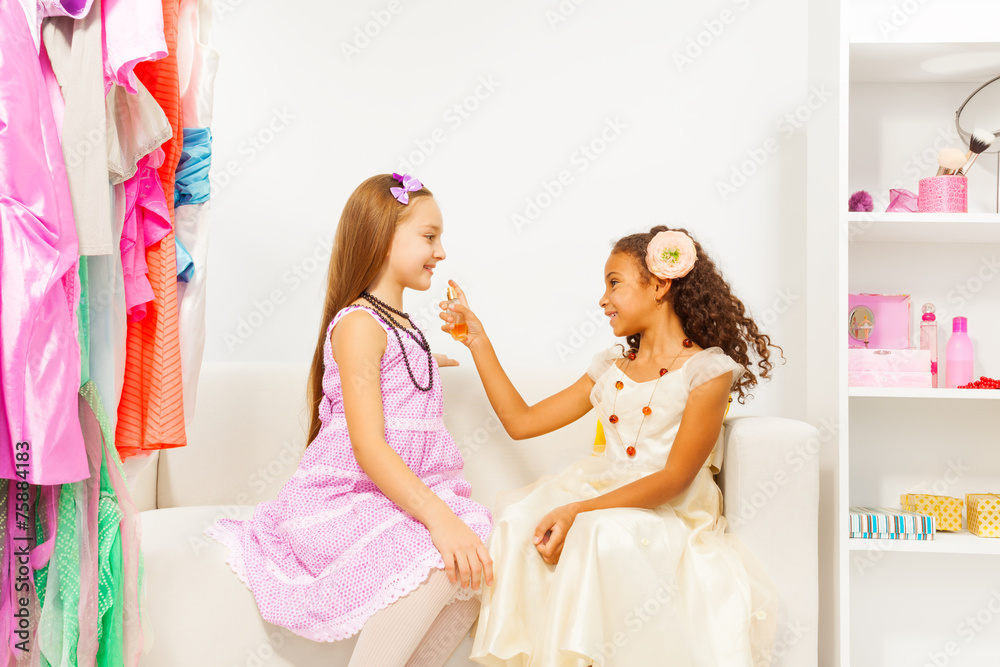 African girl applying perfume  on her friend