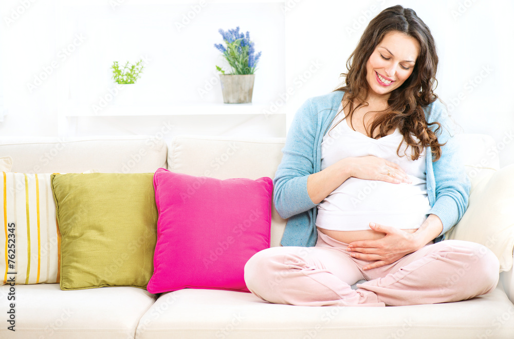 孕妇坐在沙发上抚摸自己的肚子