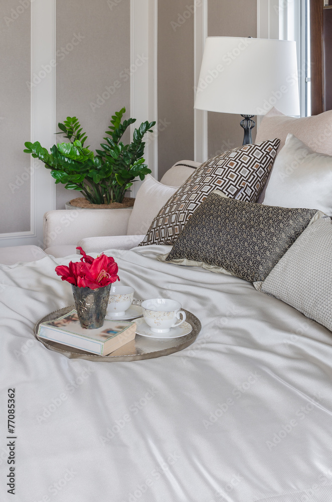 卧室床上放着一托盘鲜花、茶杯和书