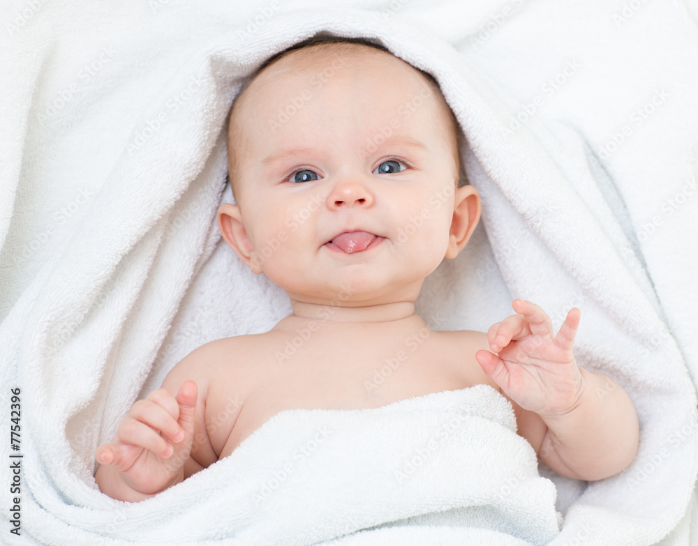 可爱有趣的婴儿穿着浴巾露出舌头