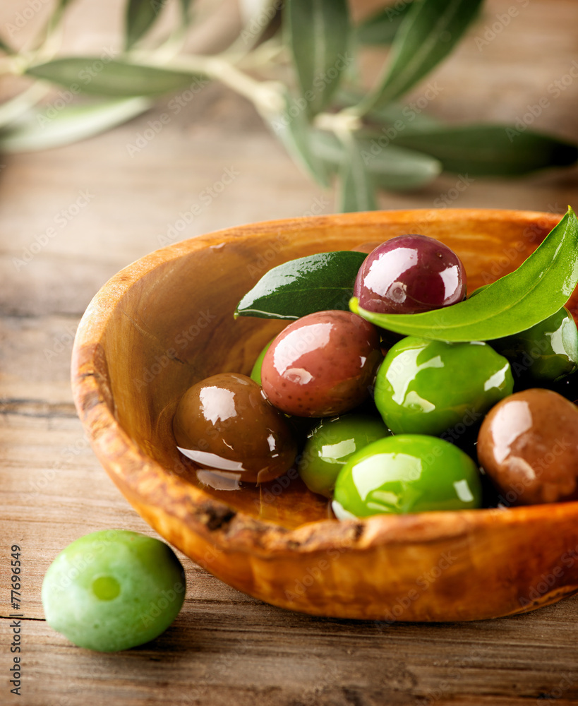 木桌上的橄榄和橄榄油。垂直图像