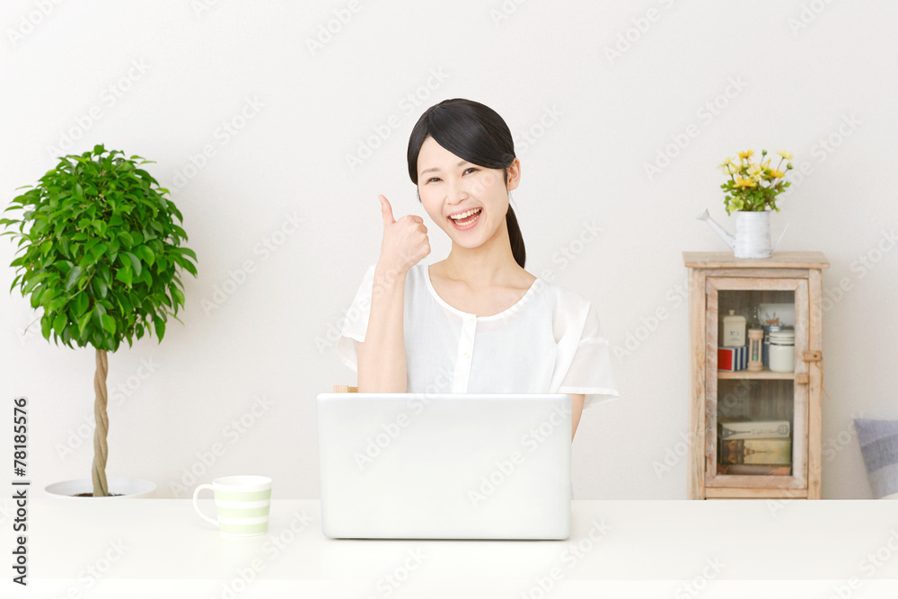 パソコンの前でグッドサインする女性