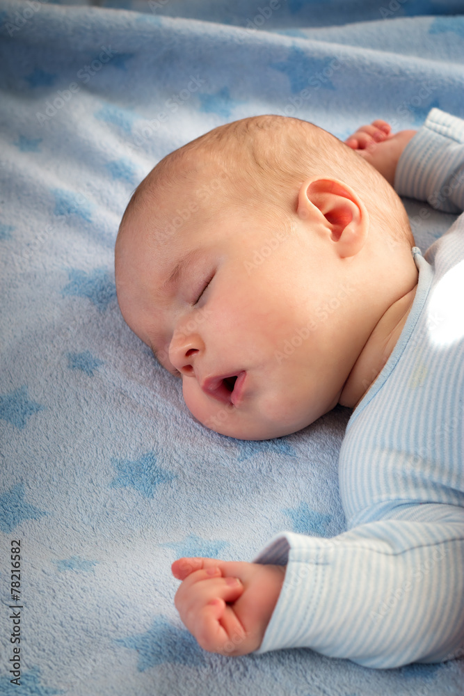 3个月大的婴儿睡在蓝色毯子上