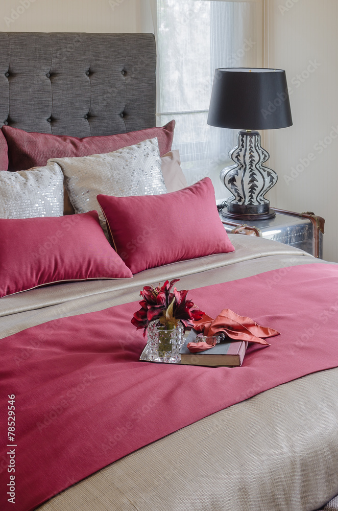 红色床和枕头，托盘上的玻璃花瓶里有植物