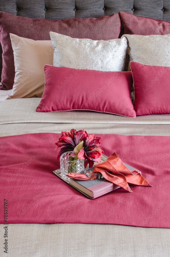 红色床和枕头，托盘上的玻璃花瓶里有植物
