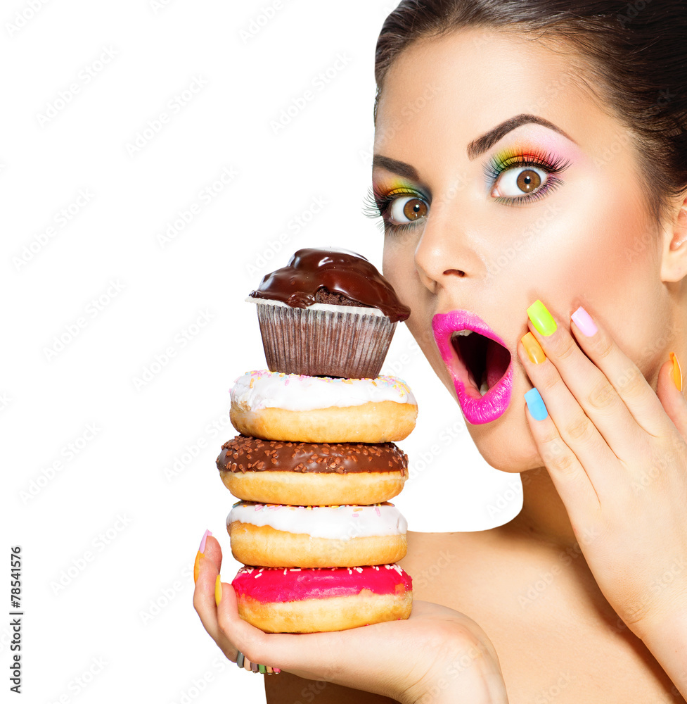 美女时尚模特女孩拿糖果和五颜六色的甜甜圈