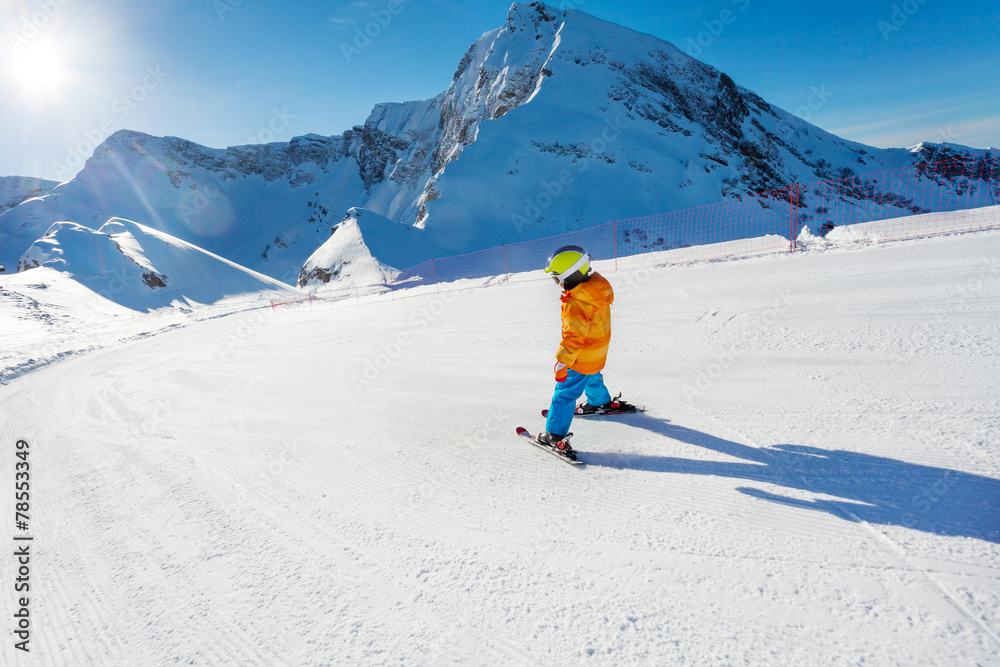 男孩在滑雪道上运动，从后面看滑雪