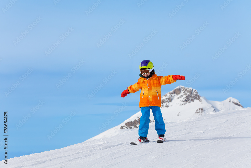 戴着滑雪面罩，双臂分开的男孩在冬天滑雪