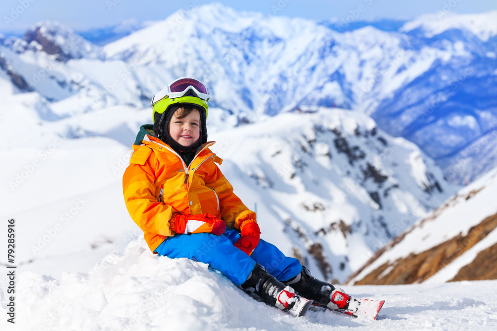 冬天坐着的男孩戴着滑雪面罩和头盔