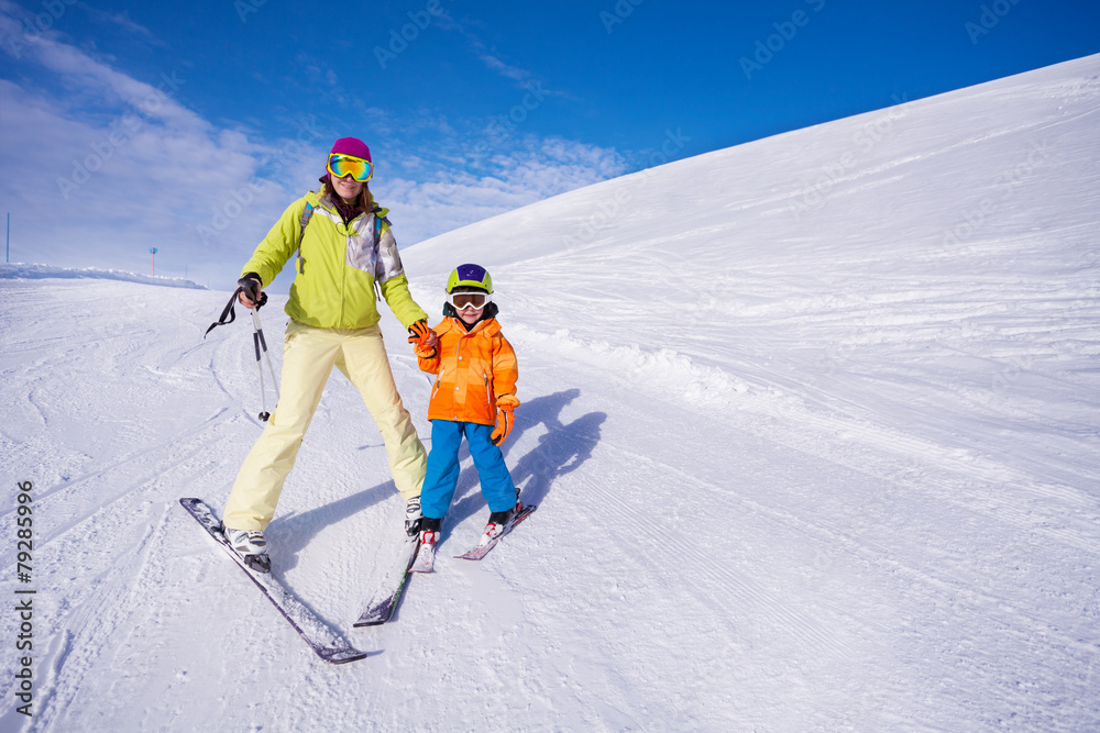 妈妈和小男孩手牵着手学习滑雪