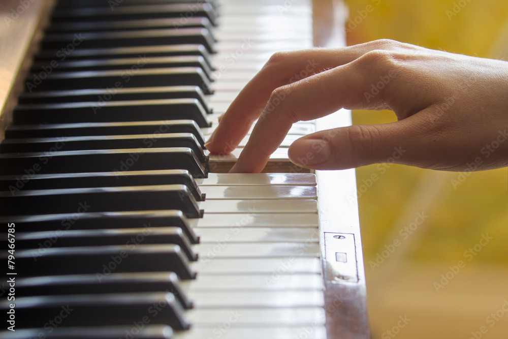 女孩右手手指按住钢琴上的音符键