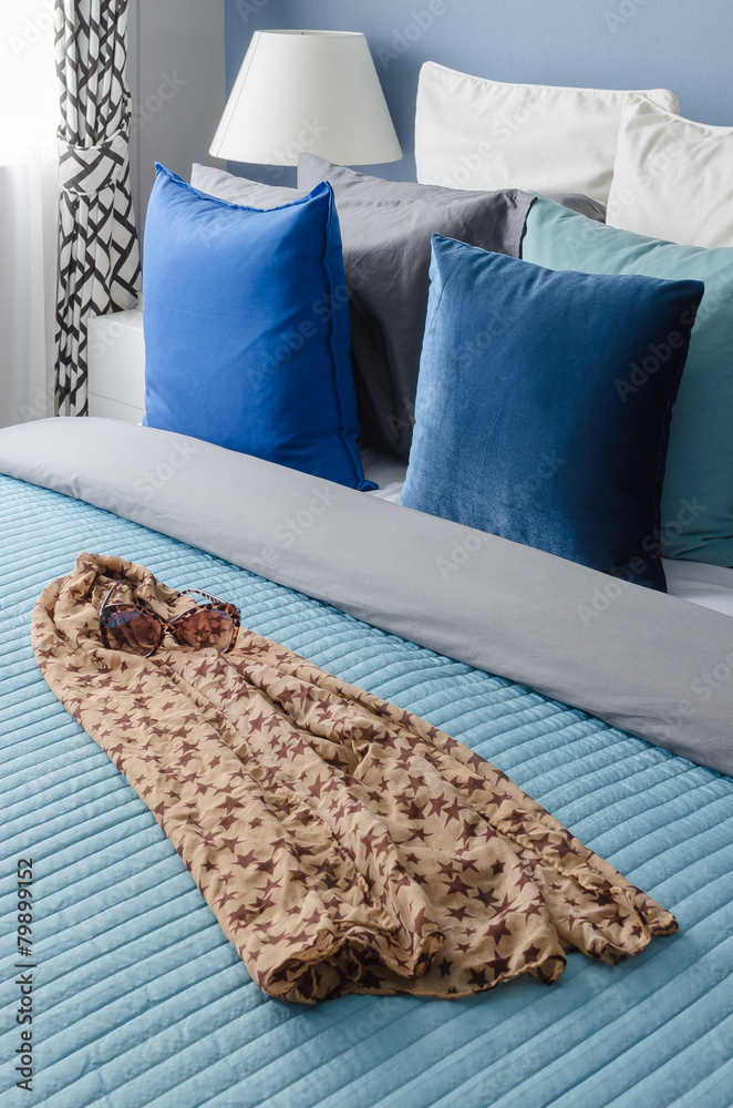 现代卧室床上的蓝色枕头，布上的眼镜
