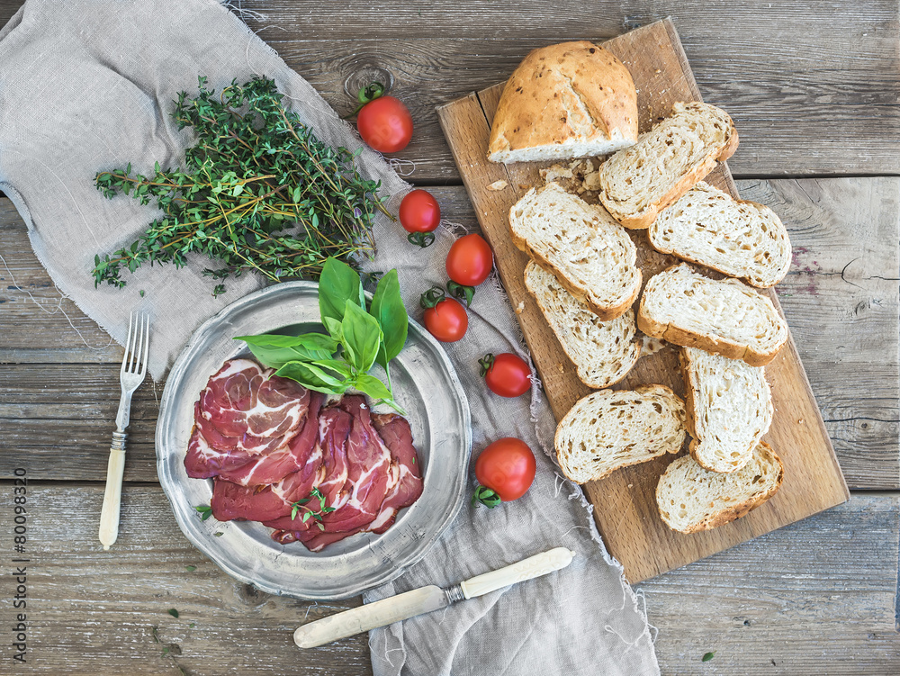Smoked meat with fresh basil, cherry-tomatoes and bread slices