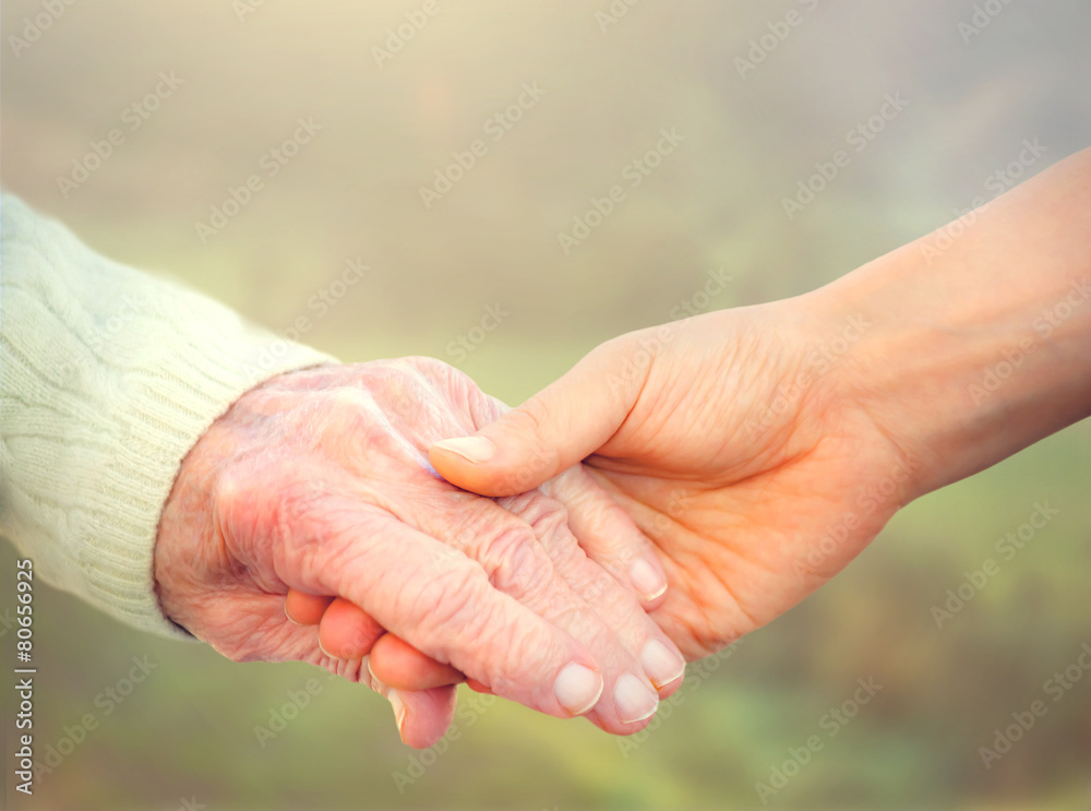 老年妇女与年轻看护人牵手