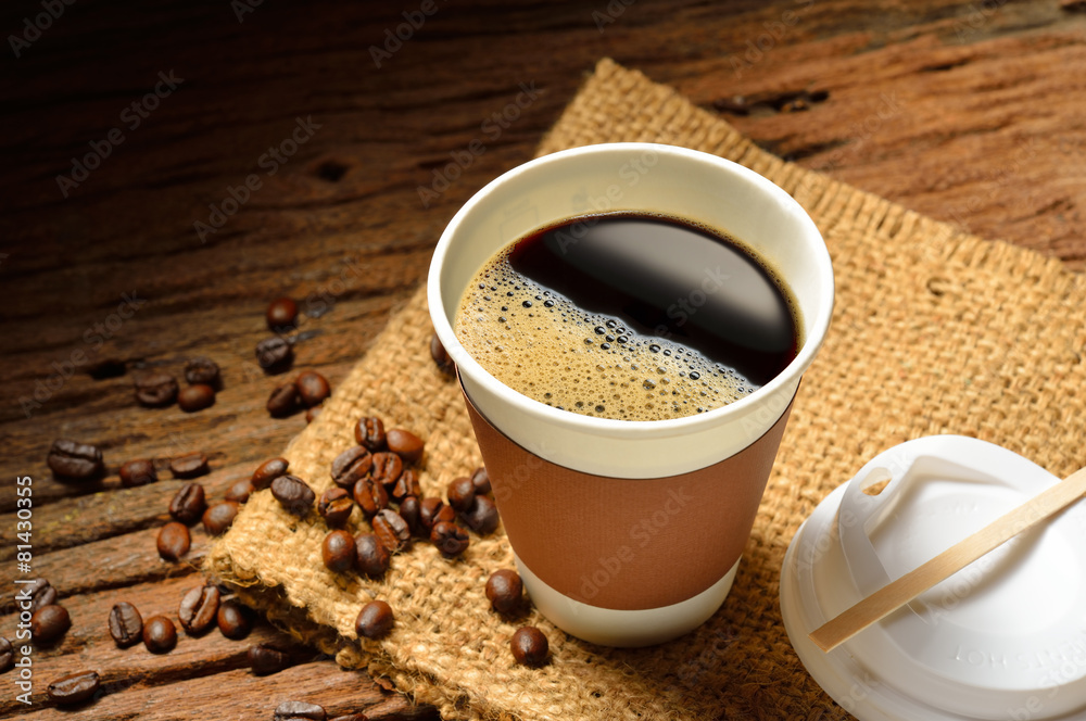 木桌上的纸杯咖啡和咖啡豆