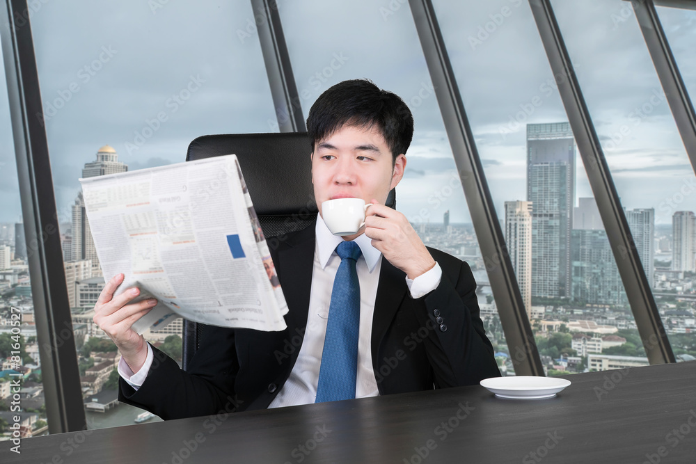 一个商人在休息时一边看报纸一边喝咖啡