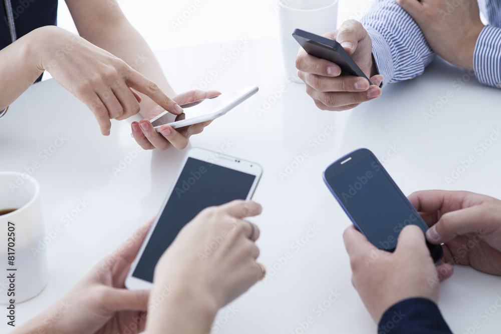Four businessmen are using a mobile phone