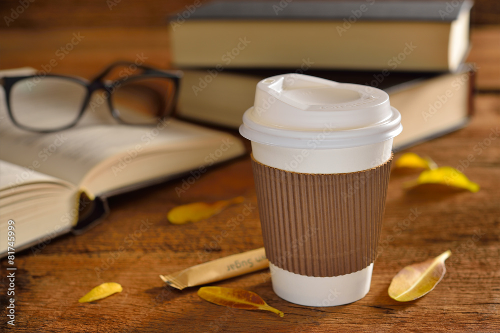 木桌上的纸杯咖啡和书籍