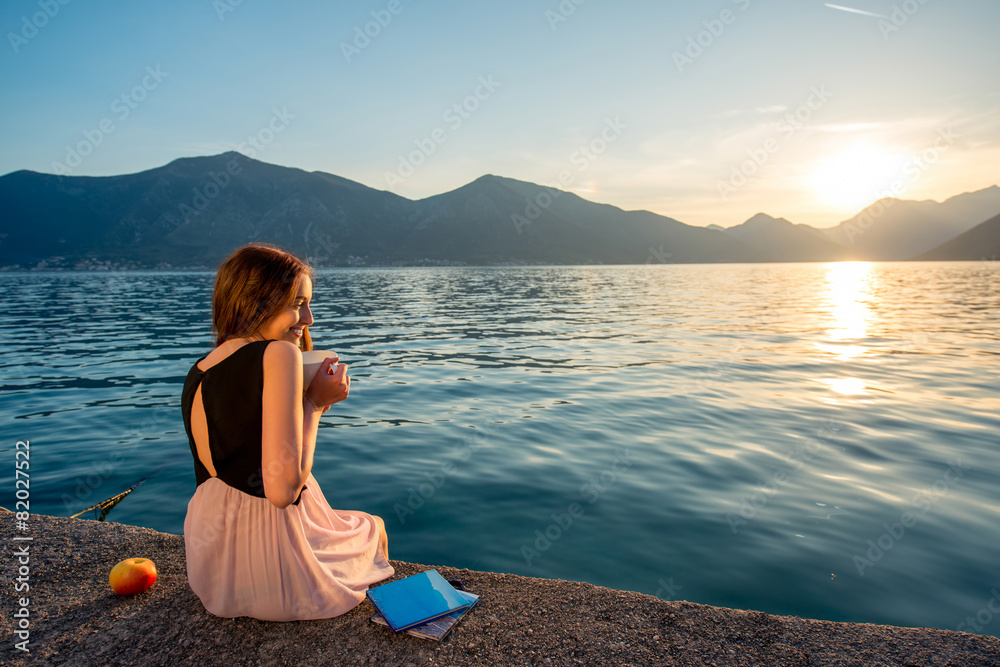 日出时坐在码头上的年轻女子